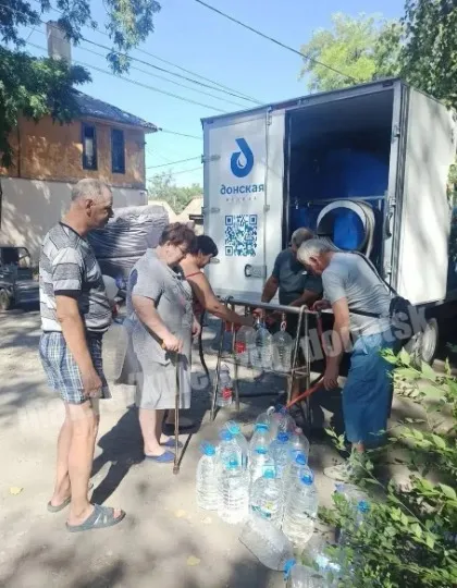 Люди стоять у черзі, аби отримати воду